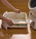 Petlibro PETLIBRO cat pet litter box tray with liner being inserted on wood floor near fountain and automatic feeder